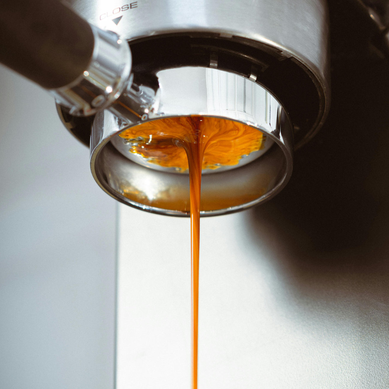 Espresso being poured from a portafilter into a coffee machine.
