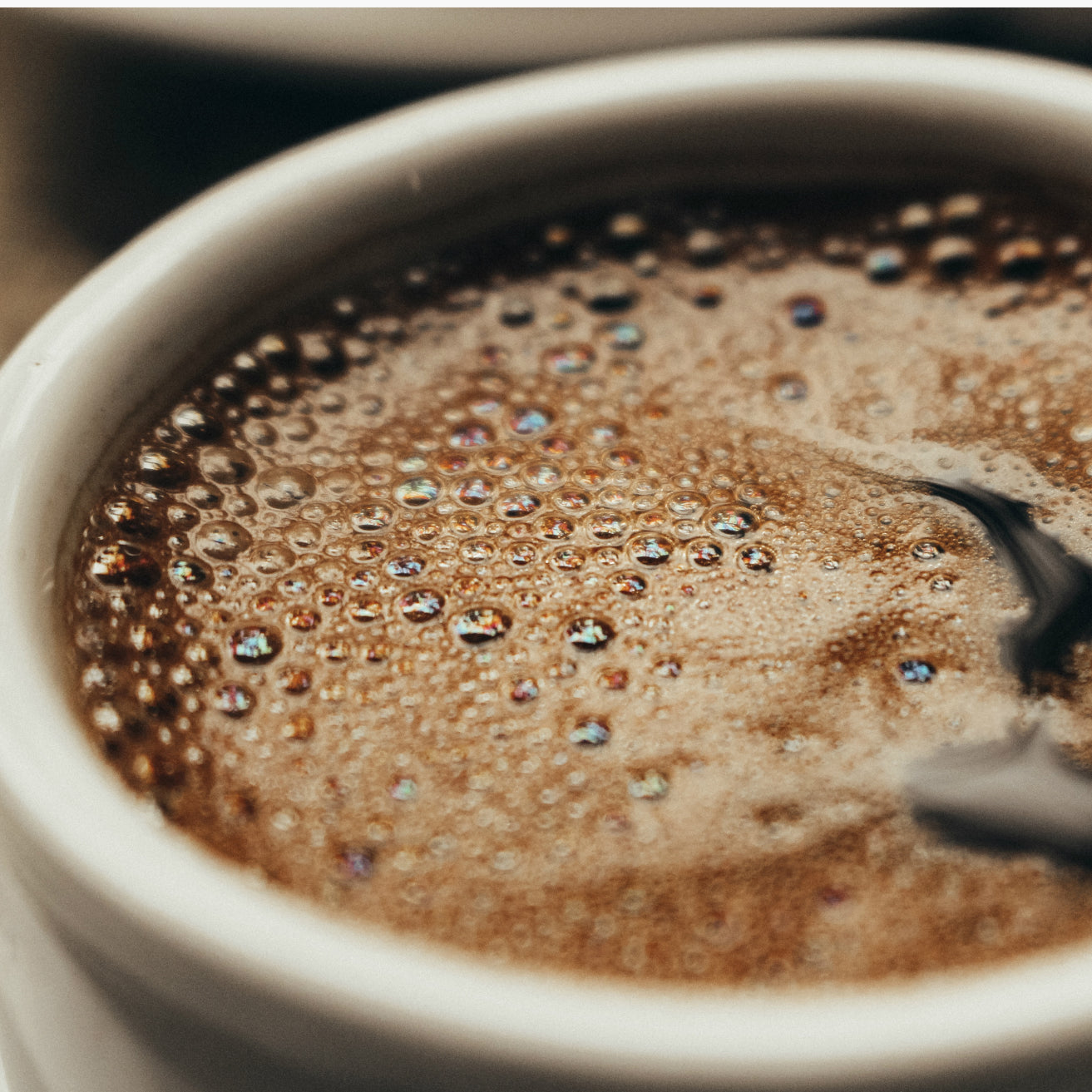 Close-up of a frothy cup of coffee with a spoon
