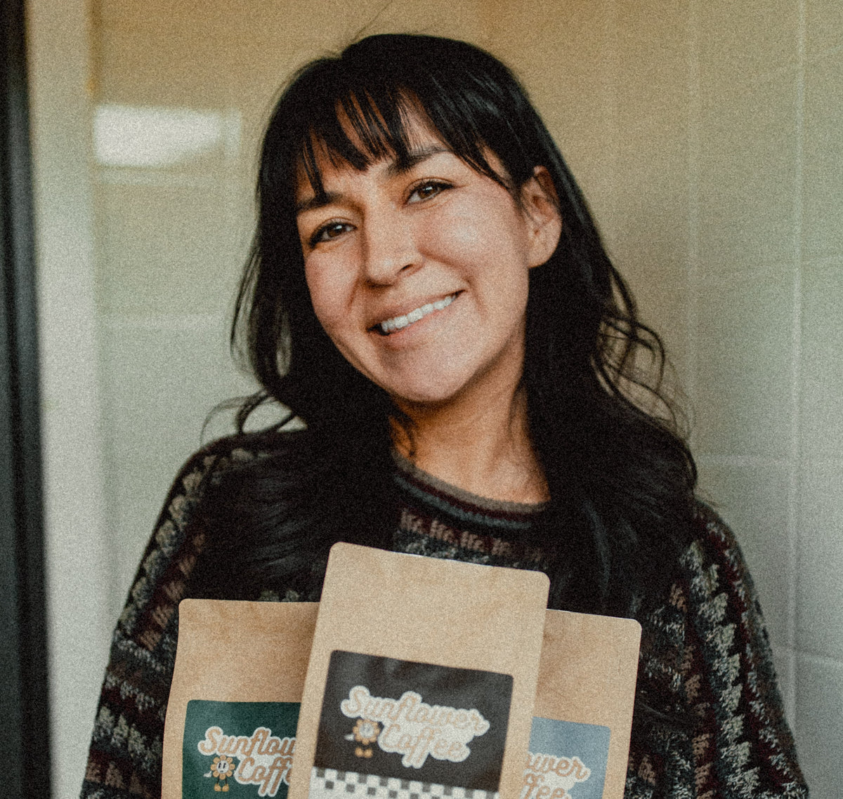Woman holding three bags of Sunflower Coffee in a kitchen setting