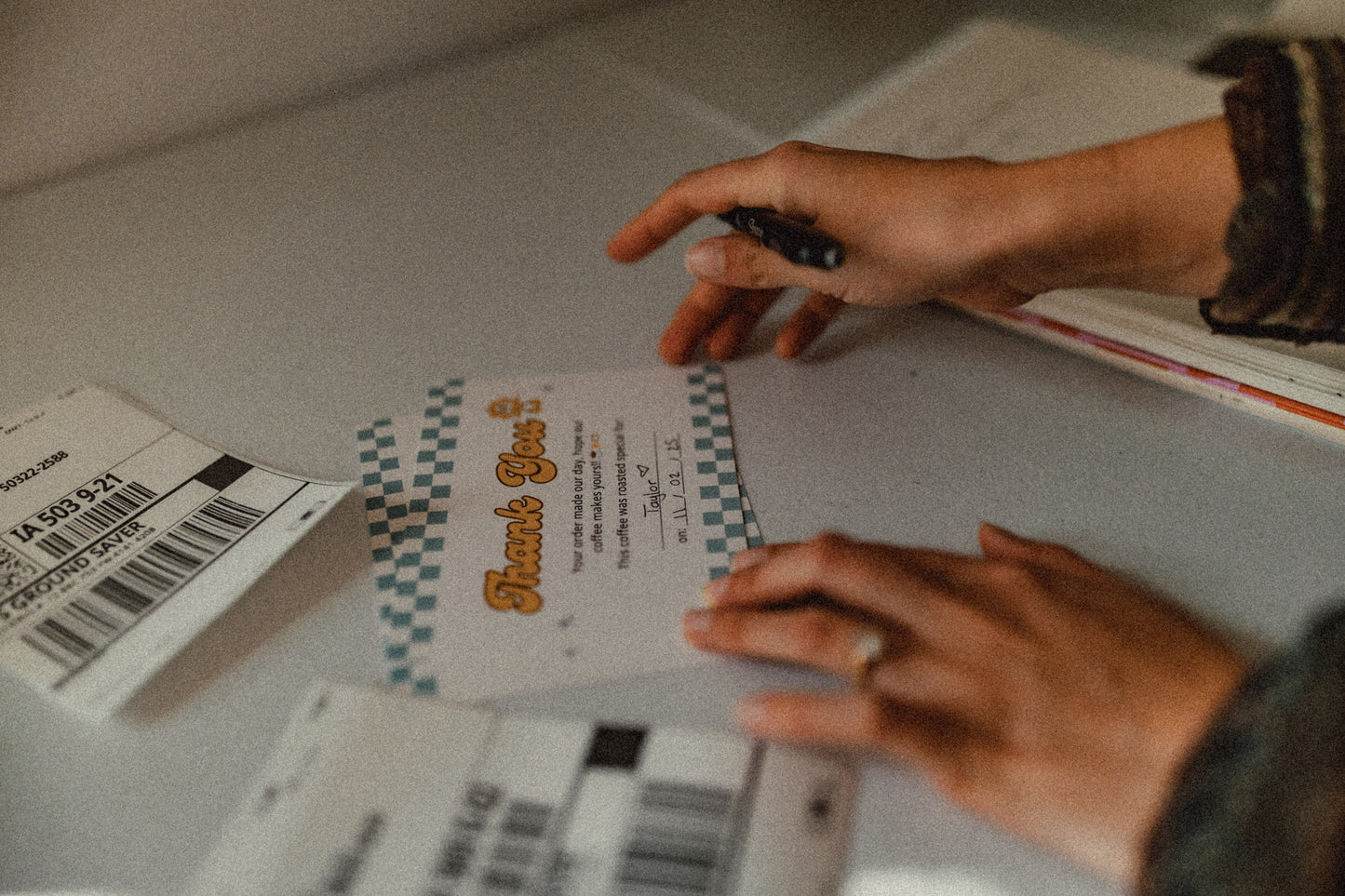 A person writing thank-you cards  on a surface