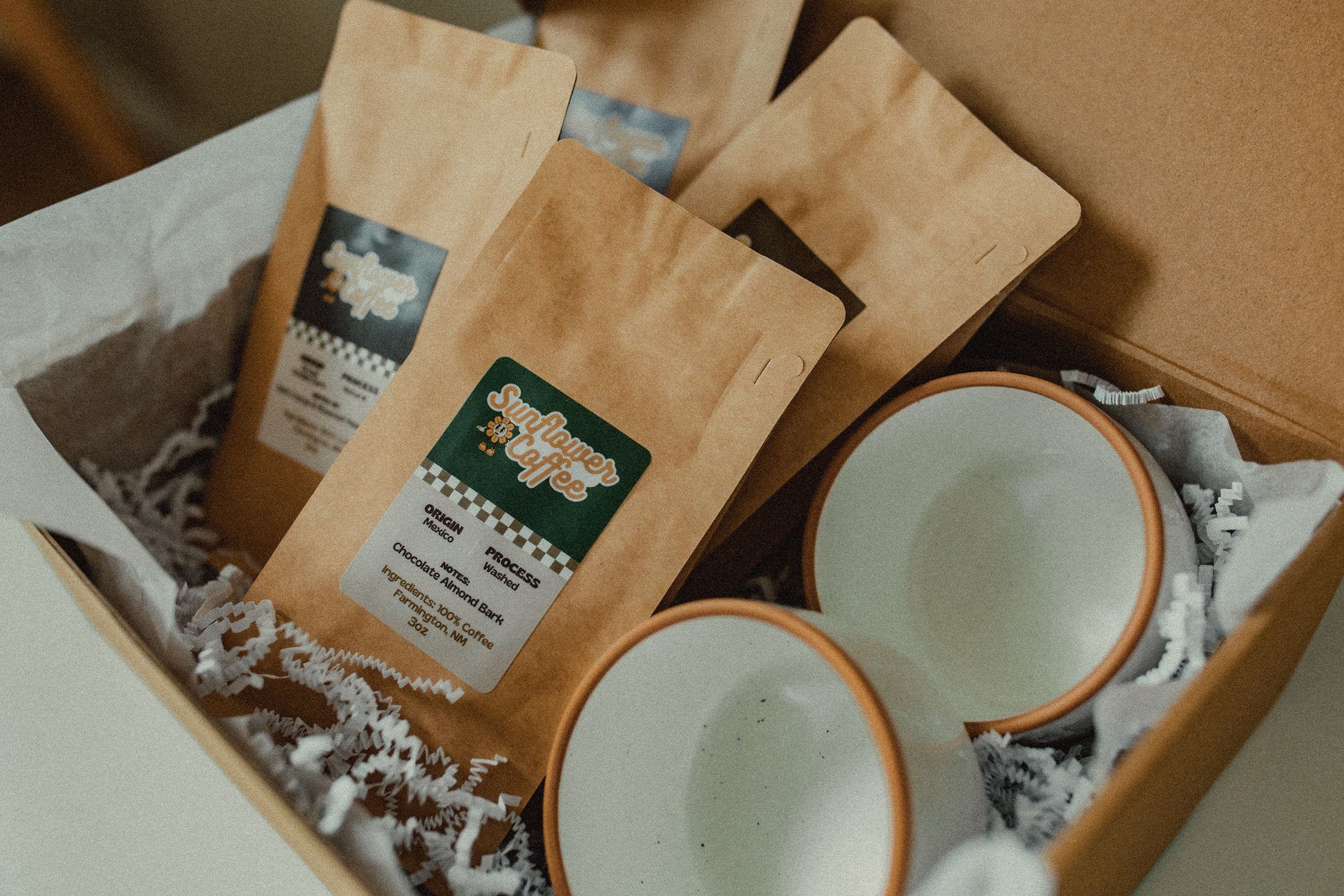 Box containing coffee packages and ceramic cups