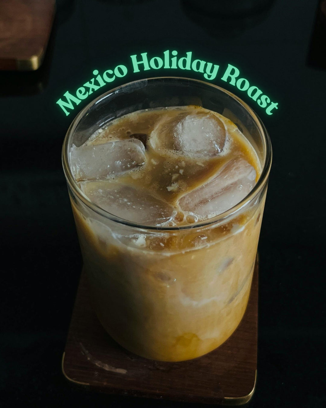 Glass of iced coffee with 'Mexico Holiday Roast' branding on a dark background